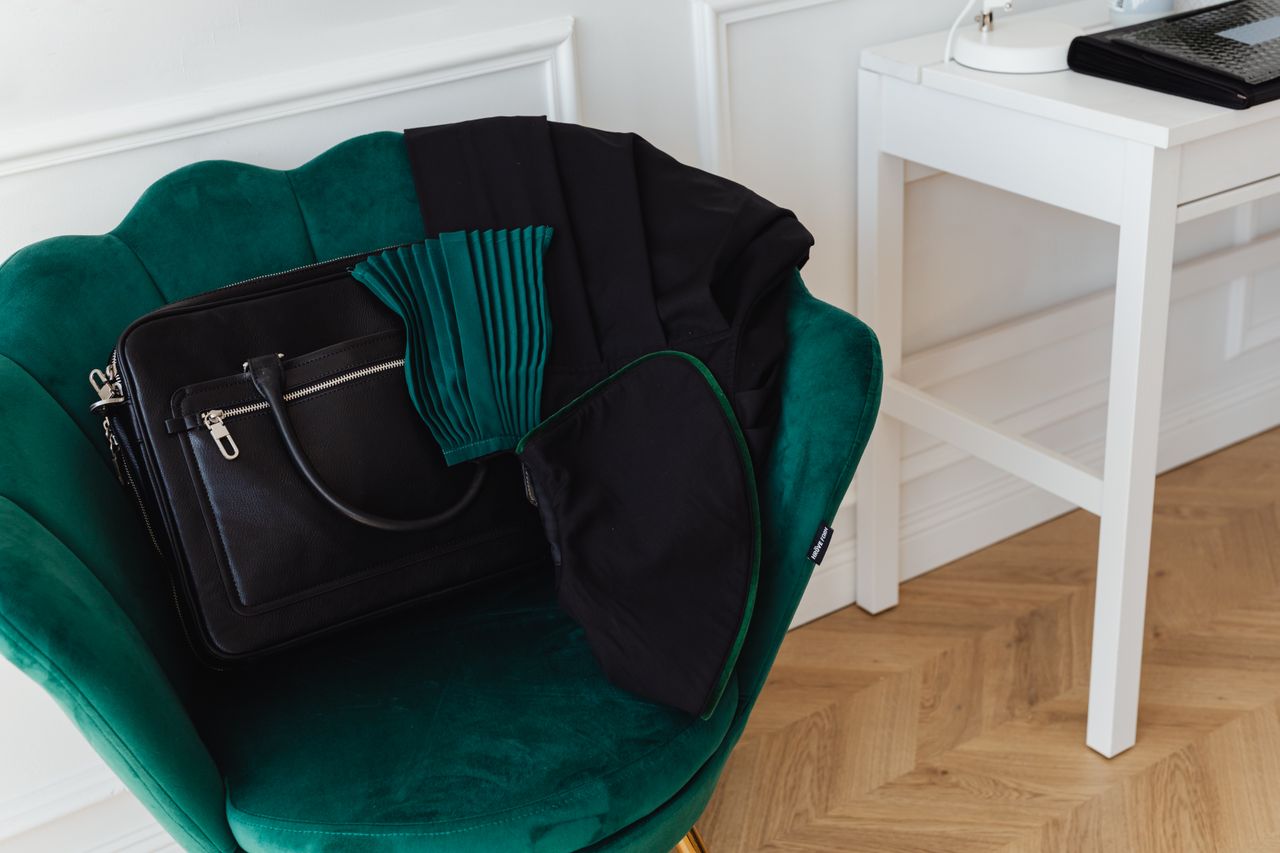 Mastering the First Impression: Your intriguing post title goes here Stylish green accent chair with a black handbag in a minimalist interior setting.